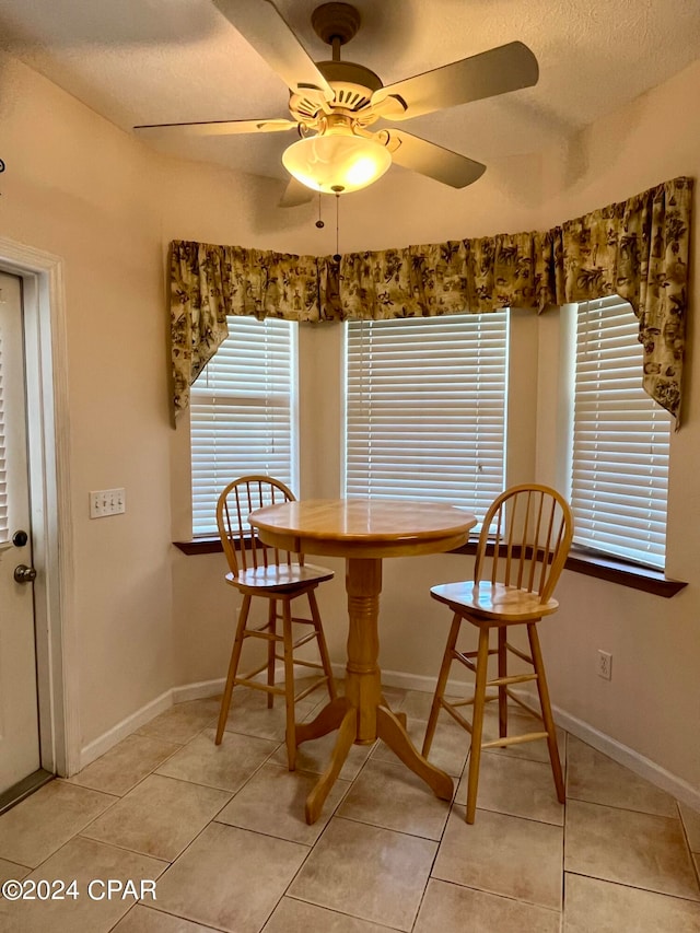 tiled dining space featuring a textured ceiling and ceiling fan