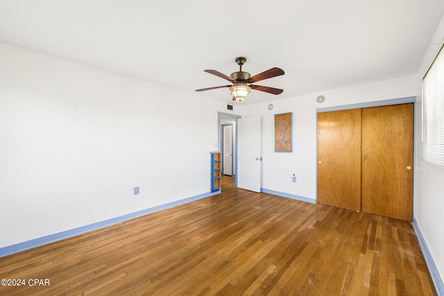 unfurnished bedroom with a closet, visible vents, a ceiling fan, wood finished floors, and baseboards