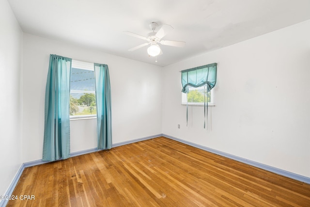 spare room with a ceiling fan, light wood-type flooring, and baseboards