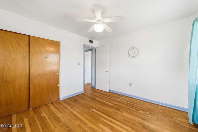 unfurnished bedroom featuring baseboards, visible vents, a ceiling fan, wood finished floors, and a closet