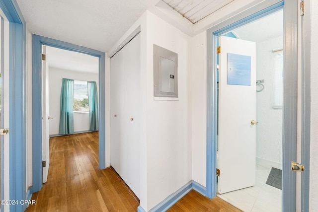 corridor with electric panel, baseboards, and wood finished floors