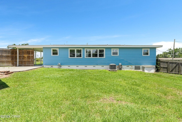 rear view of house featuring central AC unit, a lawn, crawl space, fence, and a carport