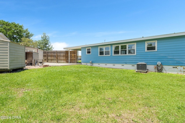 back of house featuring crawl space, fence, a lawn, and central air condition unit