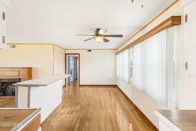 unfurnished living room featuring light wood-type flooring, visible vents, ceiling fan, and baseboards