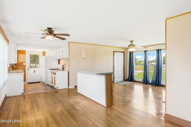 kitchen with a sink, white cabinetry, light wood-style floors, white range with gas cooktop, and light countertops