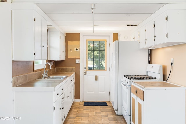 kitchen with white range with gas cooktop, white cabinetry, light countertops, and a sink