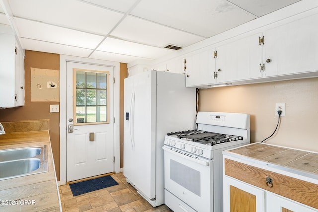 kitchen featuring a paneled ceiling, white appliances, a sink, visible vents, and white cabinets