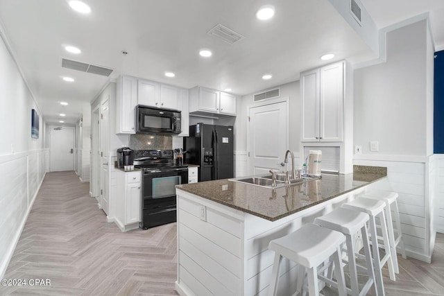 kitchen featuring white cabinets, dark stone counters, sink, and black appliances