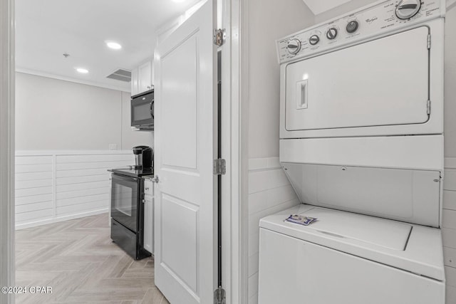 clothes washing area with light parquet floors and stacked washing maching and dryer