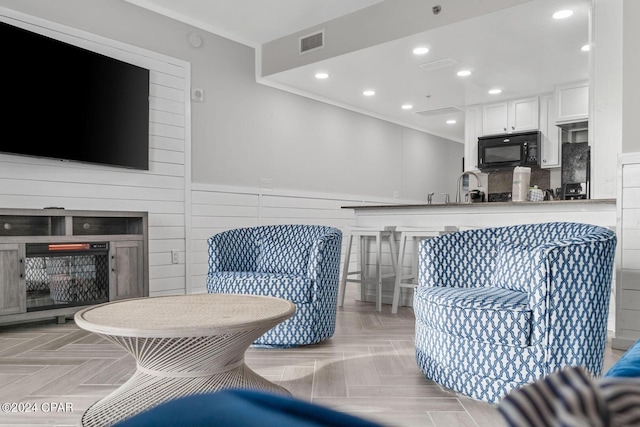 living room with ornamental molding, light parquet flooring, and sink