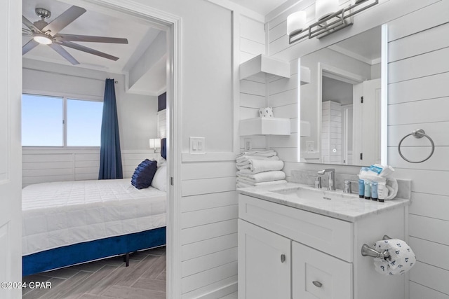 bathroom featuring ceiling fan, vanity, and wooden walls