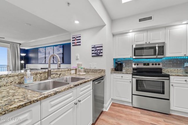 kitchen with white cabinets, sink, tasteful backsplash, stainless steel appliances, and light hardwood / wood-style floors