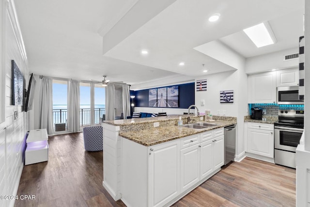 kitchen with sink, stainless steel appliances, kitchen peninsula, and white cabinetry