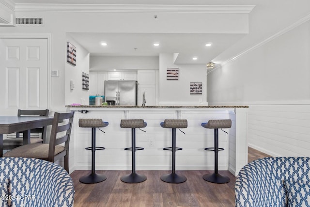 kitchen featuring a breakfast bar, white cabinets, dark hardwood / wood-style floors, and stainless steel fridge with ice dispenser