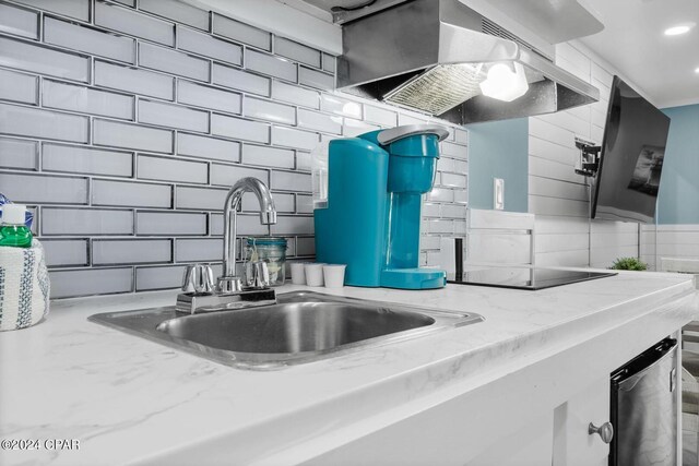 kitchen featuring backsplash, light stone counters, sink, and black electric cooktop