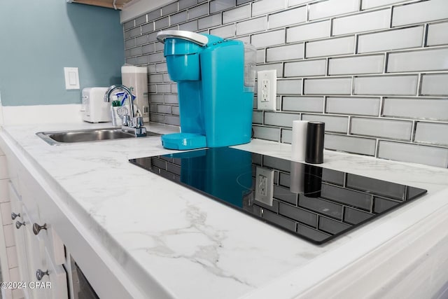 interior details with backsplash, sink, and light stone counters