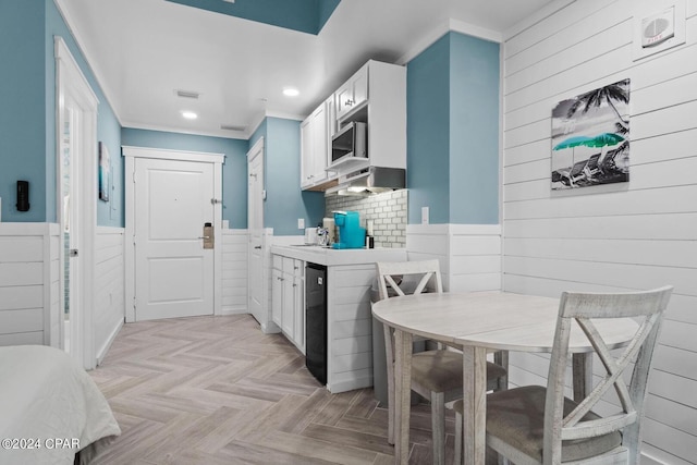 kitchen featuring decorative backsplash, white cabinets, and light parquet flooring