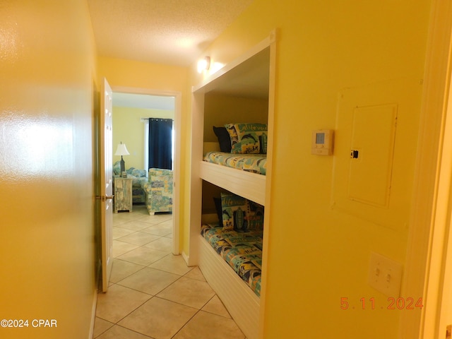 hall with tile patterned floors, electric panel, and a textured ceiling