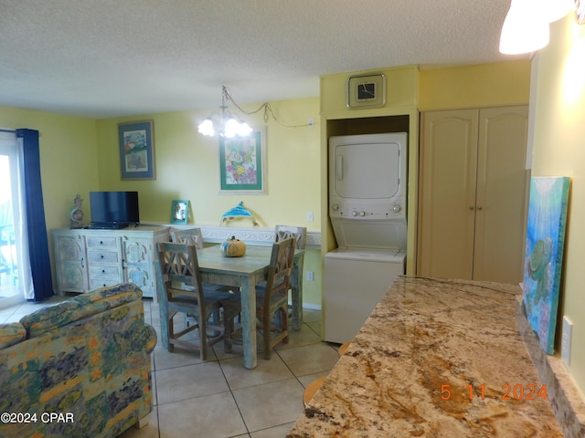 dining room featuring stacked washer / dryer, light tile patterned flooring, a textured ceiling, and an inviting chandelier