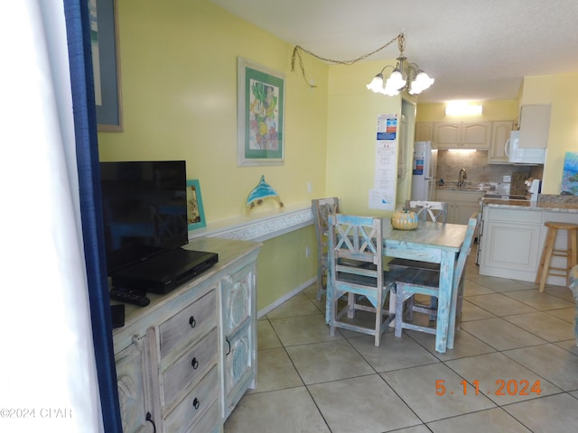 tiled dining area featuring a notable chandelier and sink