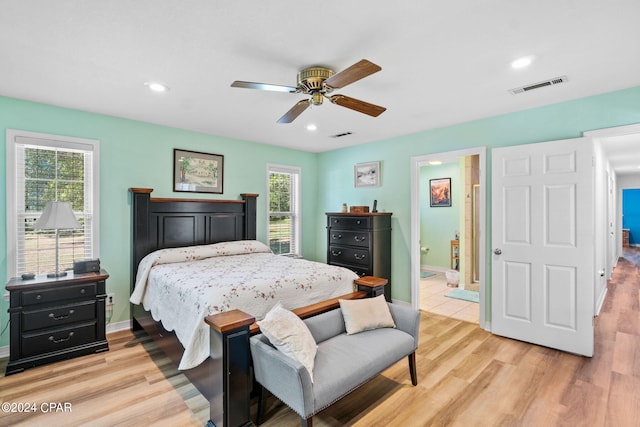 bedroom with multiple windows, ensuite bathroom, ceiling fan, and light hardwood / wood-style floors