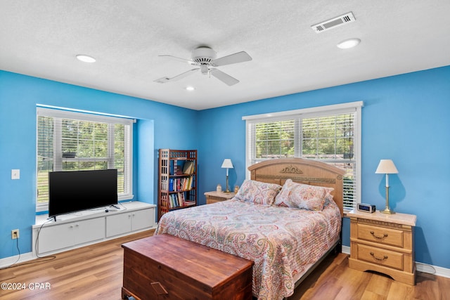 bedroom with ceiling fan, a textured ceiling, and light hardwood / wood-style flooring