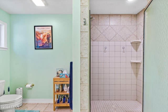 bathroom with toilet, a tile shower, and tile patterned floors