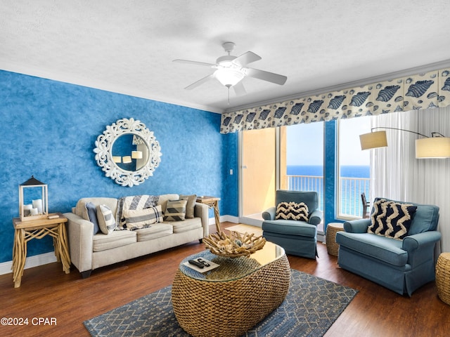 living room with a textured ceiling, a water view, ceiling fan, and dark wood-type flooring