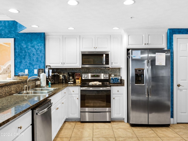 kitchen with white cabinetry, sink, dark stone countertops, light tile patterned floors, and appliances with stainless steel finishes