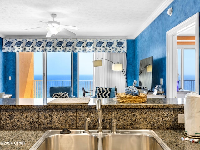 kitchen featuring sink, ceiling fan, a water view, and crown molding