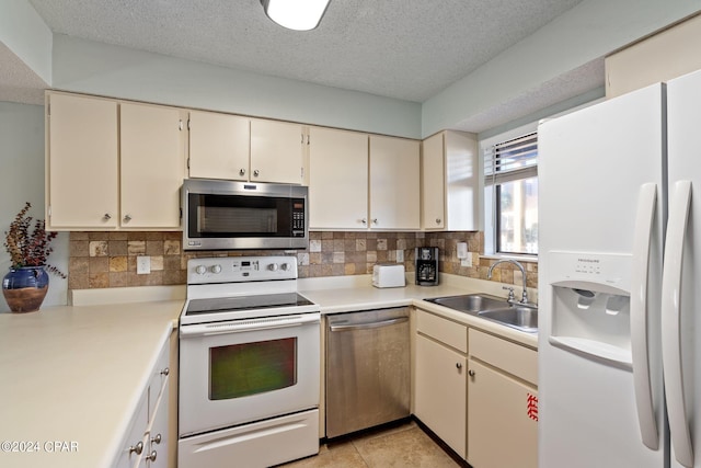 kitchen featuring a textured ceiling, stainless steel appliances, cream cabinets, and sink