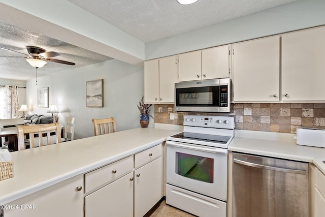 kitchen with a textured ceiling, appliances with stainless steel finishes, white cabinetry, decorative backsplash, and ceiling fan