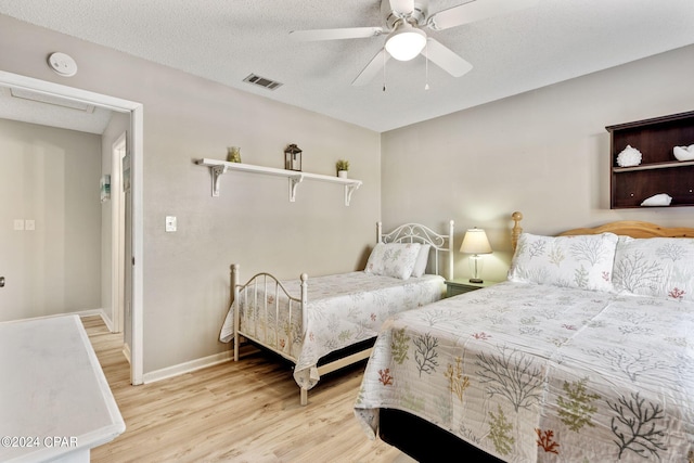 bedroom with ceiling fan, a textured ceiling, and light wood-type flooring