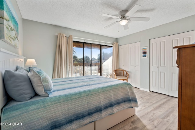 bedroom with a textured ceiling, two closets, access to outside, ceiling fan, and light hardwood / wood-style flooring