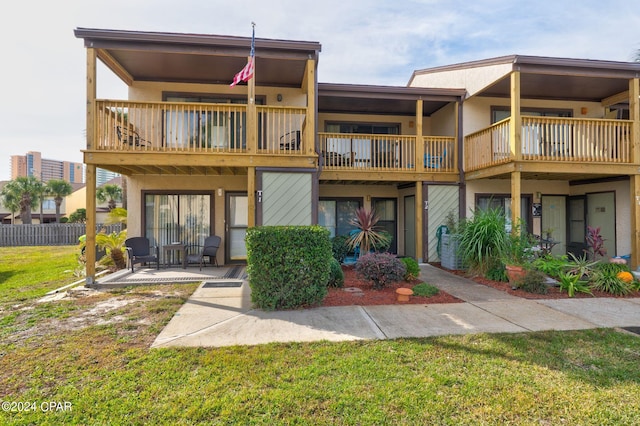 rear view of house with a balcony, a patio area, and a yard