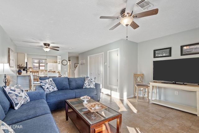 living room with ceiling fan, a textured ceiling, and light tile patterned floors