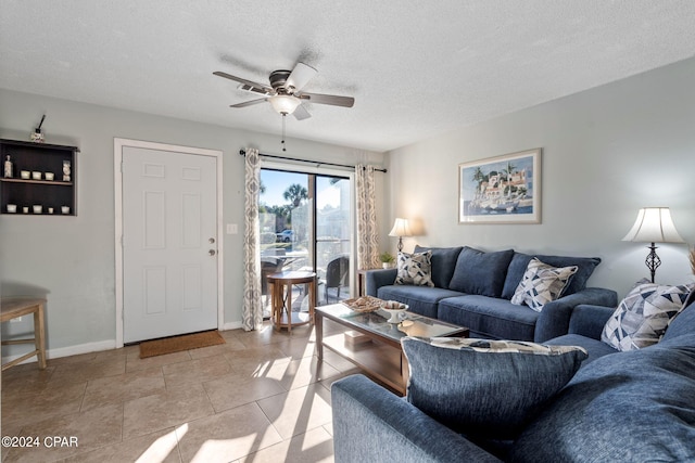 living room with ceiling fan, a textured ceiling, and light tile patterned flooring