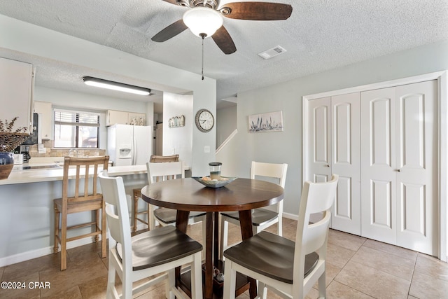 dining space featuring ceiling fan, light tile patterned floors, and a textured ceiling