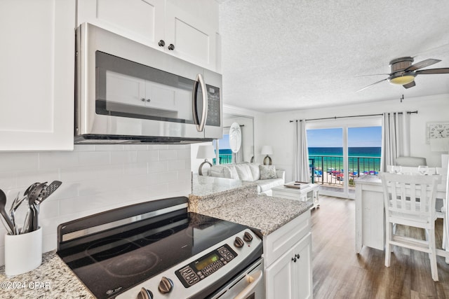 kitchen featuring white cabinets, appliances with stainless steel finishes, dark hardwood / wood-style flooring, and light stone counters