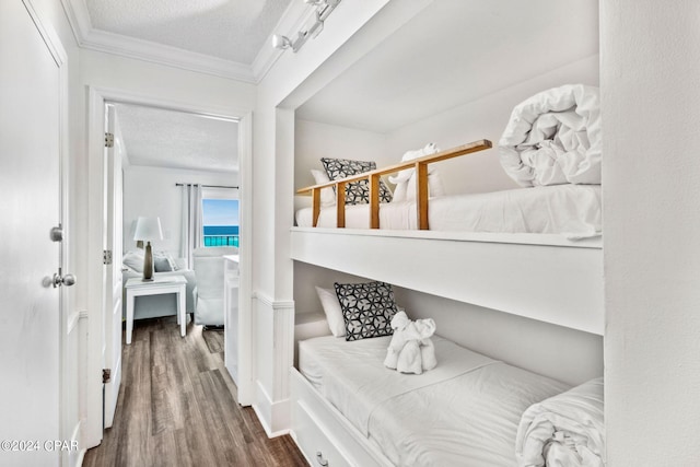 bedroom featuring dark hardwood / wood-style floors, ornamental molding, and a textured ceiling