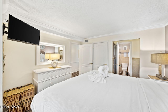 bedroom with ensuite bathroom, a textured ceiling, and ornamental molding