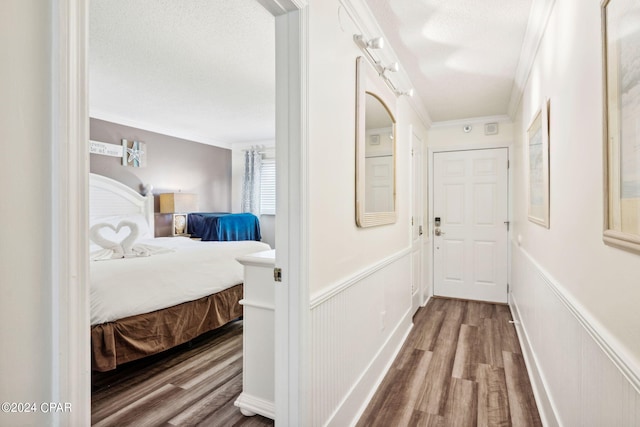 hallway featuring a textured ceiling, wood-type flooring, and crown molding