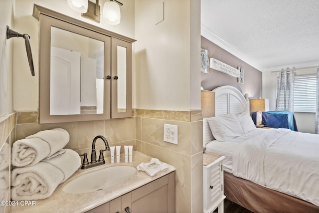 bathroom with a textured ceiling, vanity, crown molding, and tile walls