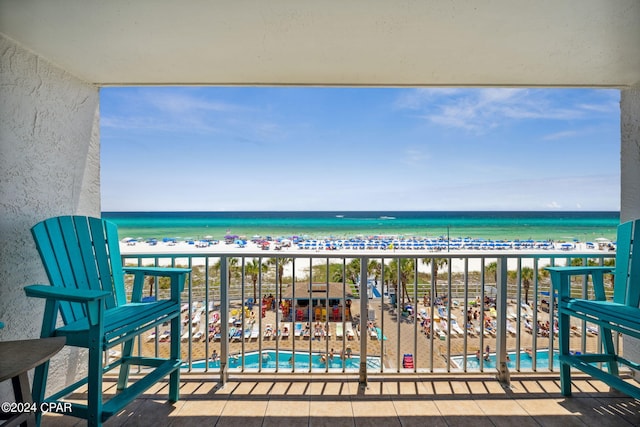 balcony featuring a view of the beach and a water view