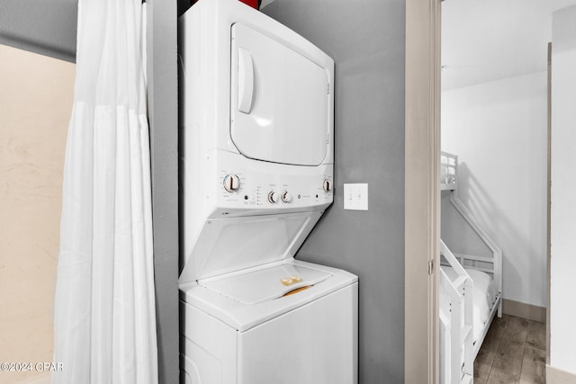 clothes washing area with stacked washer / drying machine and hardwood / wood-style flooring