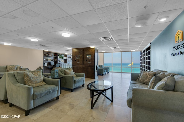 living room featuring a paneled ceiling and a wall of windows