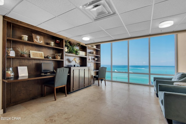 office with a drop ceiling, floor to ceiling windows, and built in shelves