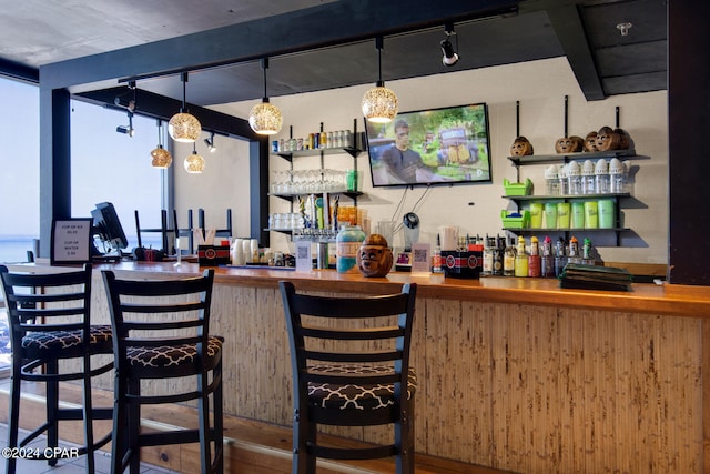 bar featuring butcher block counters, pendant lighting, track lighting, and hardwood / wood-style flooring