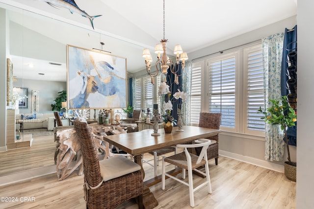 dining room featuring lofted ceiling, light wood-type flooring, and an inviting chandelier