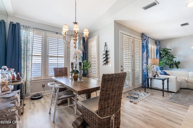 dining space with light hardwood / wood-style flooring and a notable chandelier